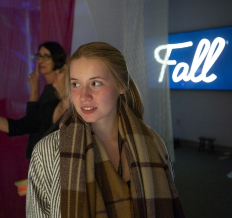A woman lighted by a neon "fall" sign